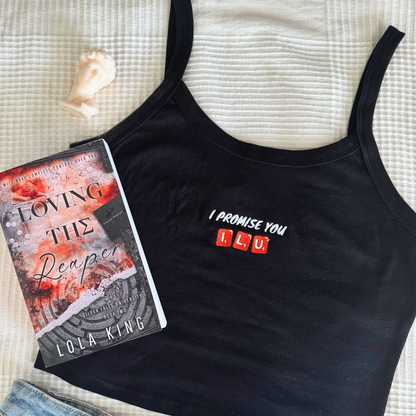 flay lay of a black tank top with the embroidery text "I promise you ILU scrabble stones. Together with the book Loving the Reaper by Lola King Merch